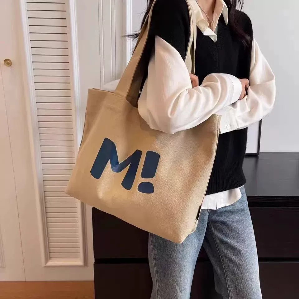 Model carrying canvas shopping tote over shoulder