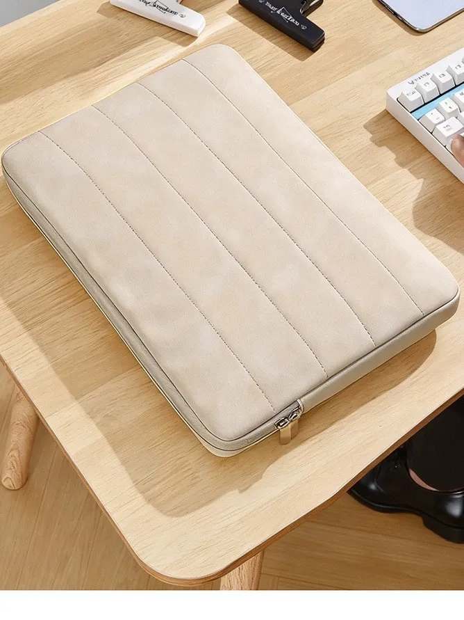 Beige quilted laptop sleeve on wooden desk with laptop