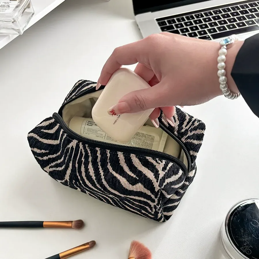 Chenille zebra pouch styled with makeup brushes on a vanity