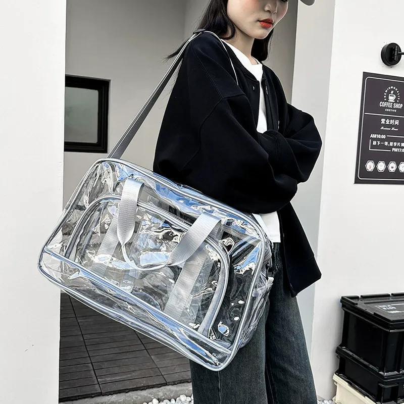 Model carrying transparent PVC travel duffel over shoulder indoors