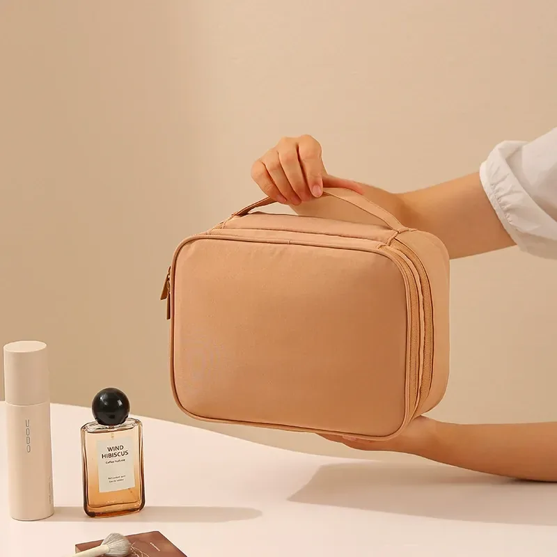 Khaki double-layer makeup organizer held by hand, divided compartments