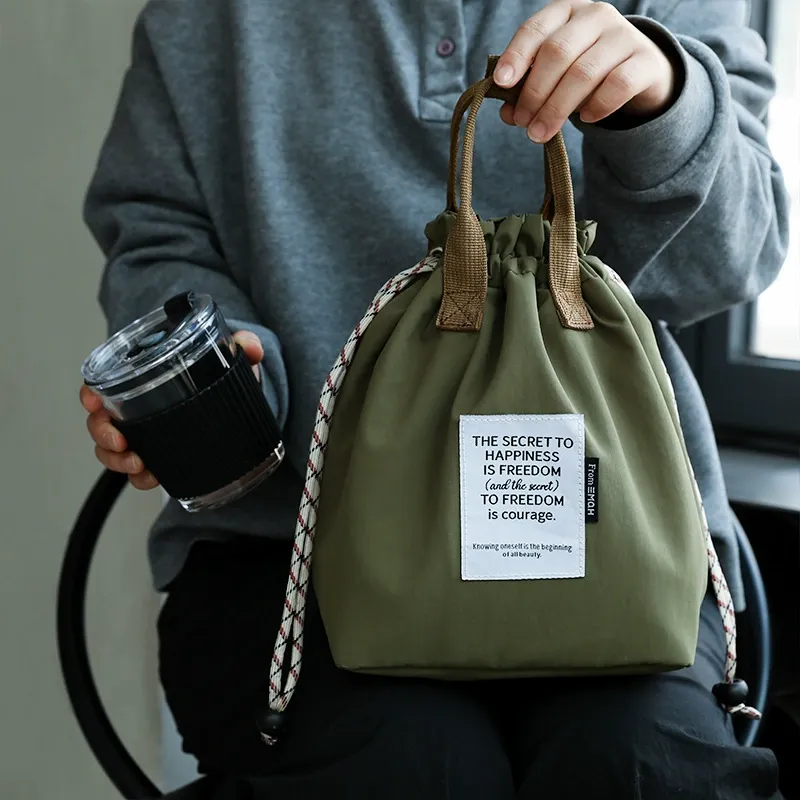Olive insulated drawstring lunch bag carried by hand with travel cup