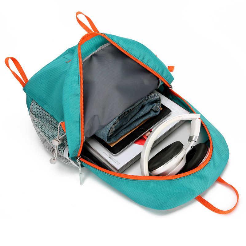 Beige lightweight hydration pack with orange adjustment straps and expandable mesh pocket.