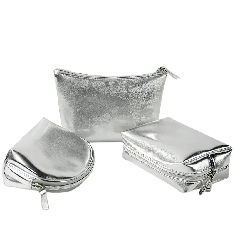 Set of three silver PU cosmetic bags in shell, trapezoid and cube shapes