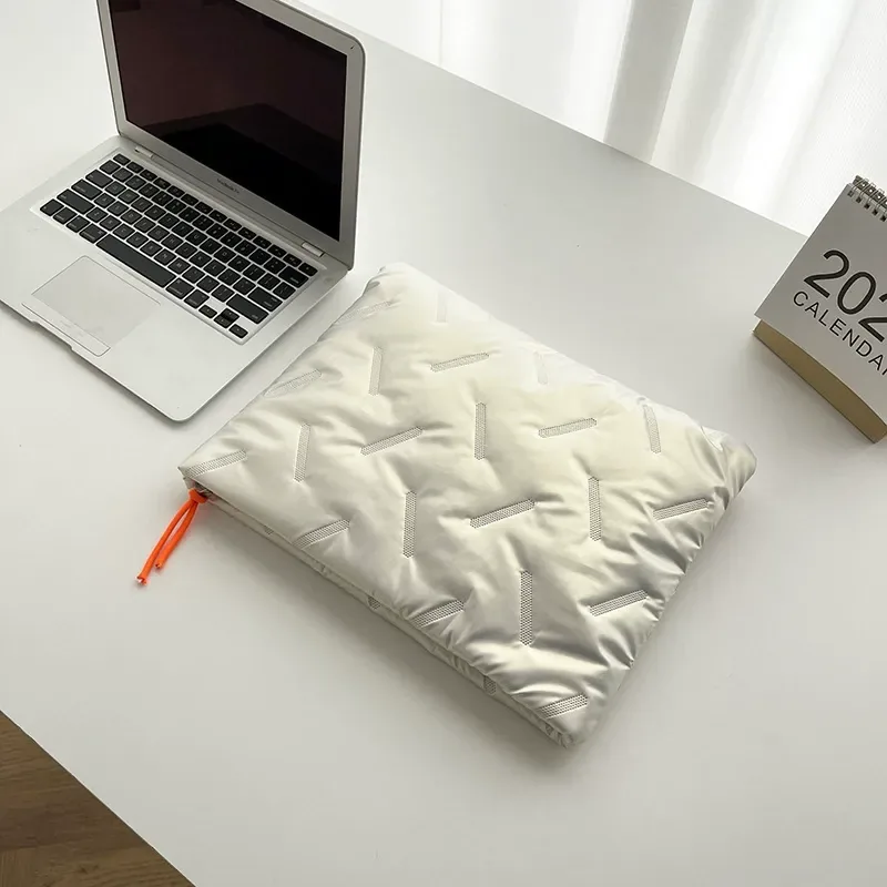 Light-color embossed waterproof laptop sleeve with orange zipper on a desk